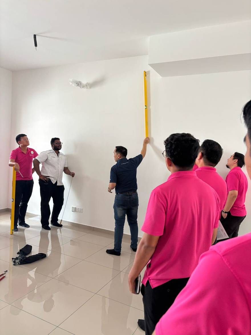 QLASSIC assessor verifying wall alignment with a spirit level during a building quality assessment