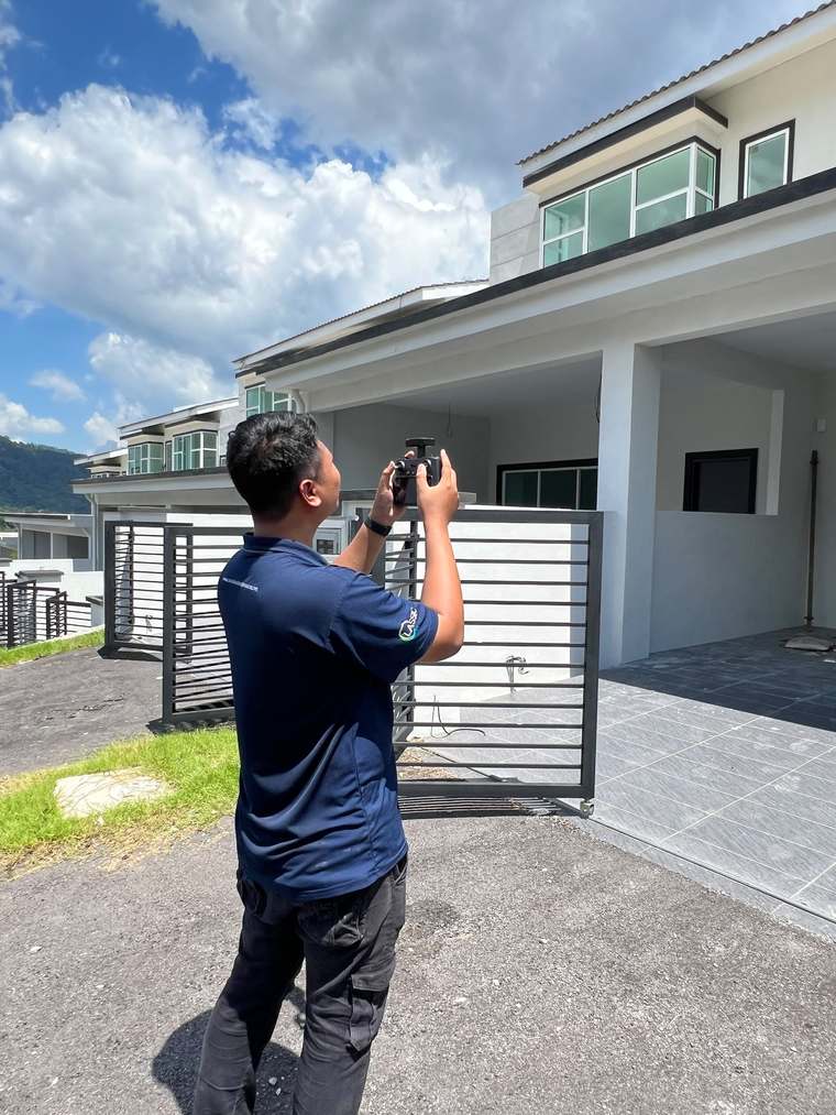 Canaan building inspector photographing and documenting the exterior of a double-storey terrace house